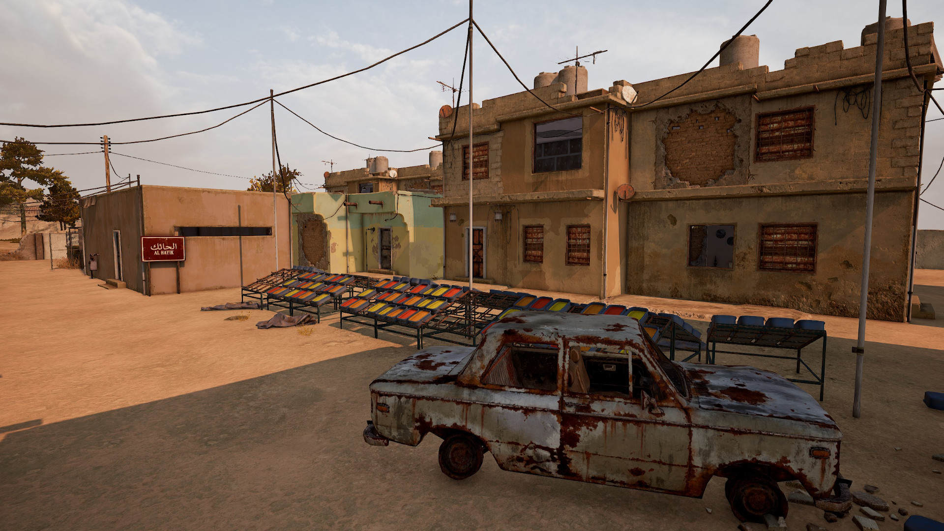 Best PUBG Karakin drops: Al Hayiq with a rusty old car next to wooden stalls and small buildings.