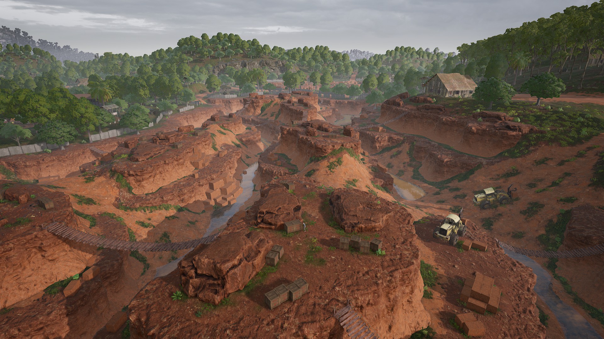 PUBG Sanhok drops: The dusty Quarry located in the middle of Sanhok, with two trucks in a gulch on the right side, and the jungle in the distance.