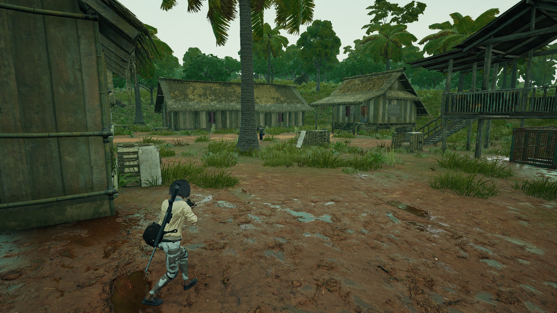 PUBG Sanhok drops: A player walking through a small village in Sanhok, with another player hiding behind a large tree at the center of the location.