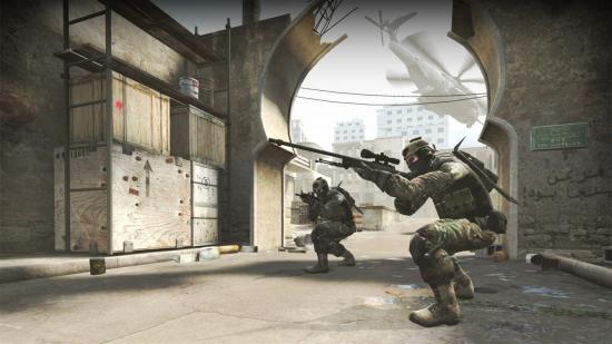 Two soldiers crouch between buildings in CS:GO, one aims a sniper rifle