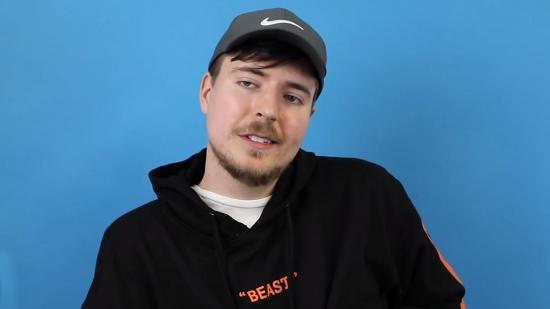 YouTuber MrBeast wearing a grey cap and a black hoodie, in front of a bright blue backdrop