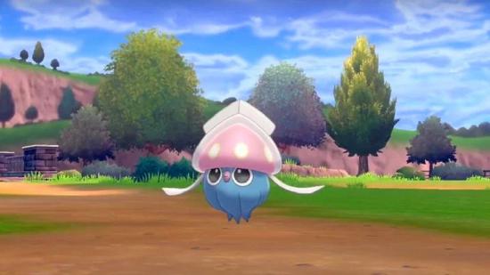 Inkay, a small squid-like Pokémon, levitates over a muddy path through a green field