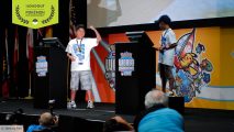 Jeremy Fan punches the air on stage, standing behind a Pokémon World Championships branded podium