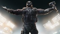 Rainbow Six Siege ranks: An operator looks up with his arms outstretched, and is holding a sledgehammer in one hand