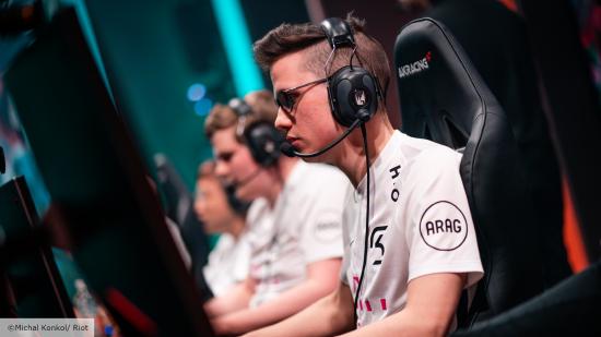 League of Legends pro Crownshot sat at a PC, wearing a white jersey, black headset, and black glasses