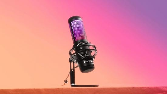 A microphone with a pink gradient top stands on a desk
