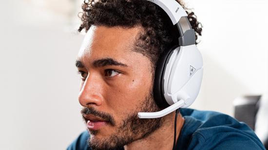A slightly bearded man wearing a white headset with a mic sticking off it