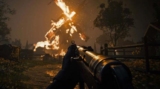A soldier with an MP40 stares at a burning windmill.