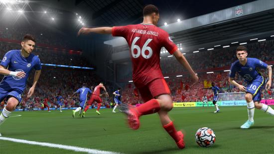 A Liverpool player in a red kit looks to cross the ball while being closed down by two Chelsea players in blue