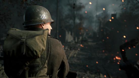 A soldier looks on at a burning forest in front
