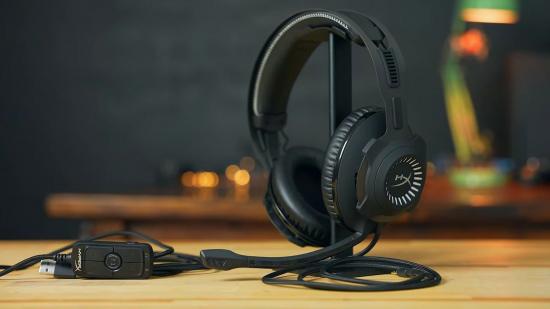 A black HyperX headset sitting on its stand on a wooden table top