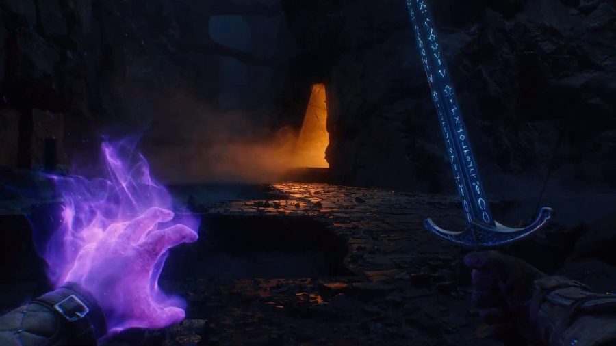 Avowed: a player's perspective can be seen, with a light coming from a cave. The player holds a sword in their right hand and casts a spell in their left.