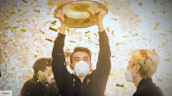 A Team Spirit Dota 2 player lifts the Aegis of Champions trophy, surrounded by gold confetti