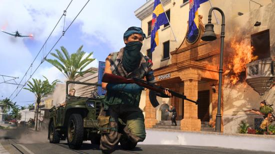 Warzone ranked: A female operator wielding an assault rifle runs down the main street of Capital in Caldera. Behind her, another operator is driving a jeep. In the background there are more operators fighting outside of the Caldera police station
