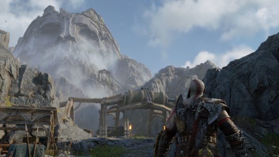 God of War Ragnarok review: Kratos stares up at a mountain that has a skeletal face carved into it and is shrouded in mist
