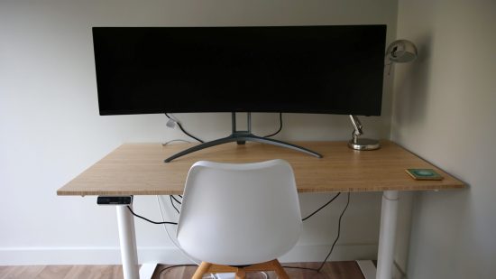 The FlexiSpot E8 standing desk with a 55-inch curved monitor on the desktop