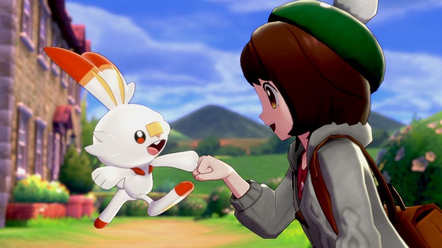 Pokémon Sword and Shield: a trainer in a green hat fist bumping Scorbunny