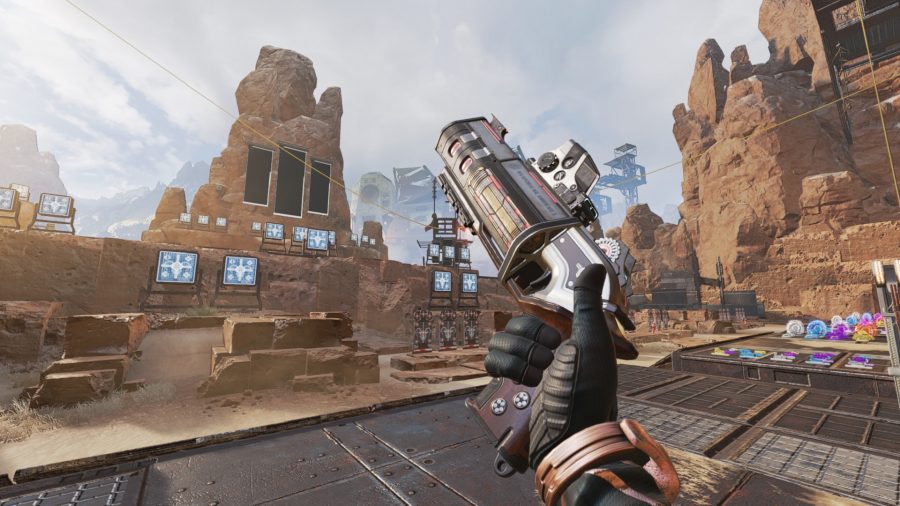A close-up inspection of the Mozambique weapon from Apex Legends. There is a desert background filled with targets behind the pistol-shotgun hybrid