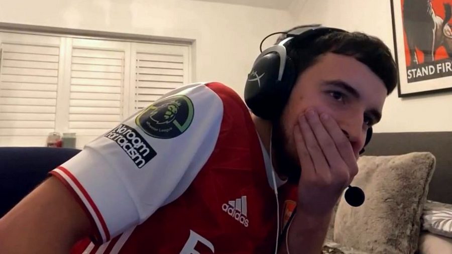 A FIFA player wearing a red Arsenal kit covers his mouth in disbelief