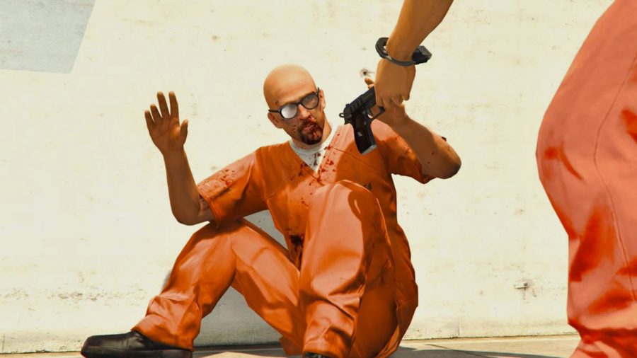 Professor Maxim Rashkovksy in an orange prison uniform raises his hands as he sits on the floor of a prison yard