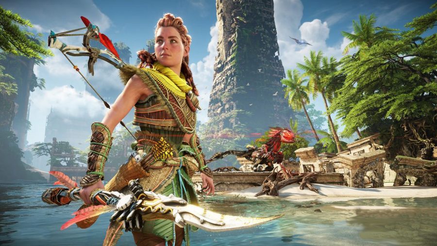 Aloy stands in front of an ancient-looking tower on a beach
