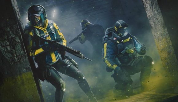 Three operators in yellow and black combat gear take up position in a dark hallway.