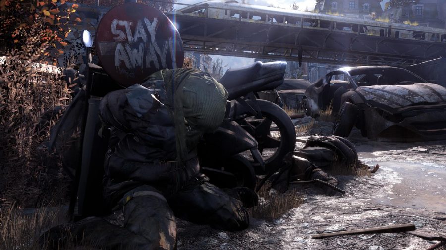 Dying Light 2 review: a dead body can be seen next to a sign that says "Stay Away"