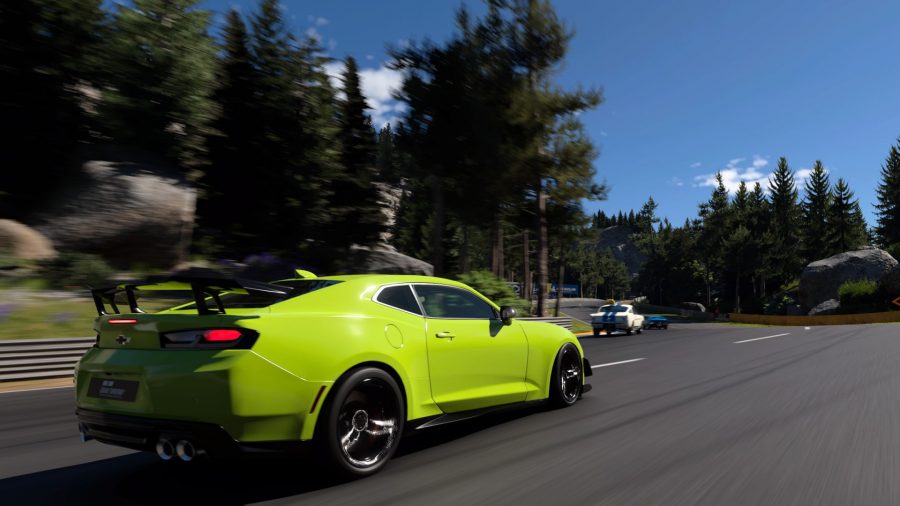 Gran Turismo 7 review: A lime green Chevrolet Camaro going round a sweeping corner. In the background are tall trees and a blue sky